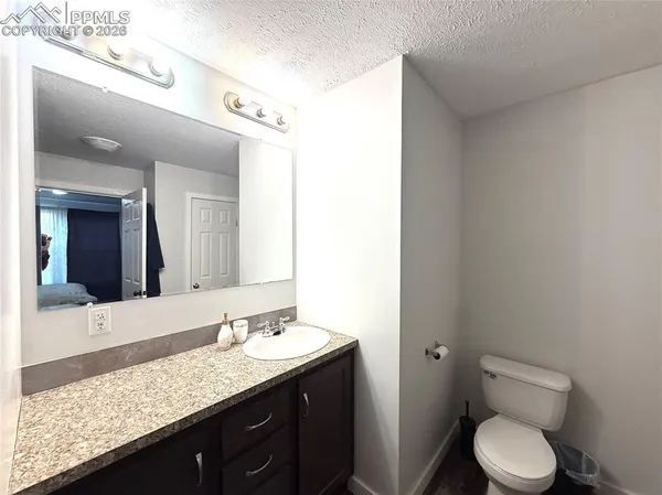 a bathroom with a granite countertop sink toilet and mirror