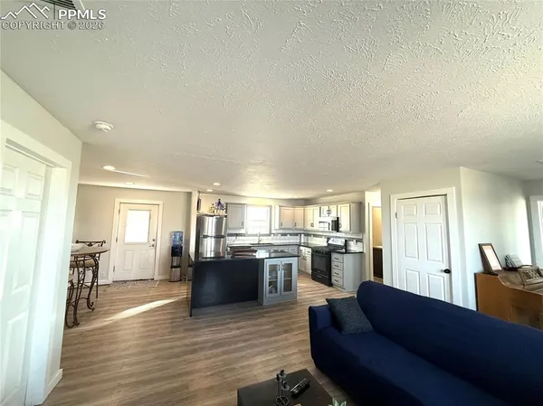 a living room with stainless steel appliances granite countertop furniture and a wooden floor