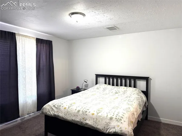 a bed sitting in a bedroom next to a window and a wooden floor