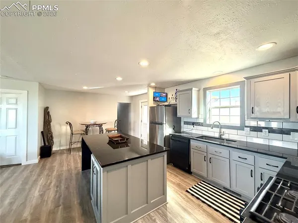 a kitchen with granite countertop a sink dishwasher stove top oven and cabinets
