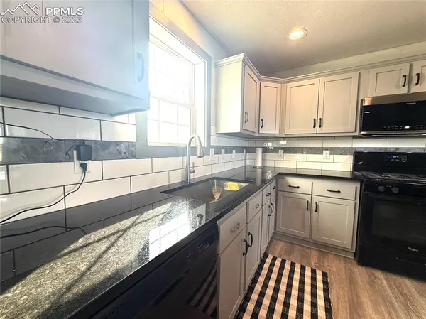 a kitchen with granite countertop a sink a window stainless steel appliances and cabinets