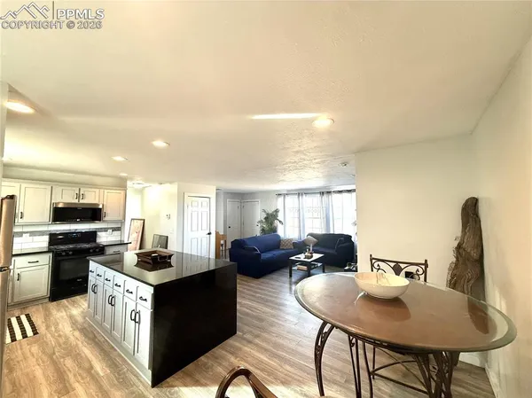 a kitchen with stainless steel appliances kitchen island granite countertop a sink dishwasher a stove a refrigerator with a dining table and chairs