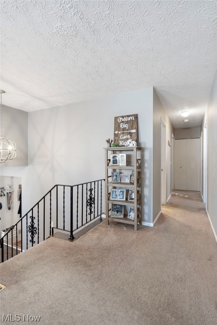 801 Netherwood Avenue Northwest Canton, OH 44708 - Photo 14 of 44 Hallway featuring a textured ceiling, light carpet, and a notable chandelier