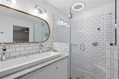 a bathroom with a sink a large mirror and a shower