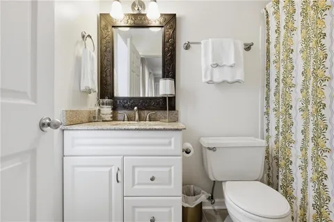 a bathroom with a granite countertop toilet sink and mirror