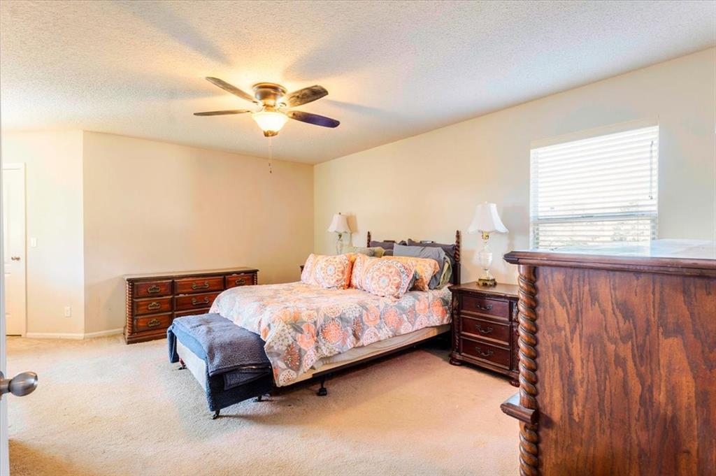 1606 Withers Way Krum, TX 76249 - Photo 13 of 35 a bedroom with a bed and a chandelier