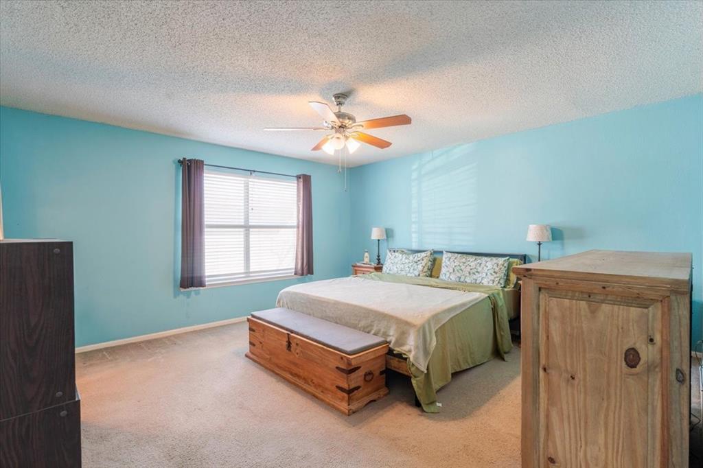 1606 Withers Way Krum, TX 76249 - Photo 21 of 35 a spacious bedroom with a bed and a chandelier