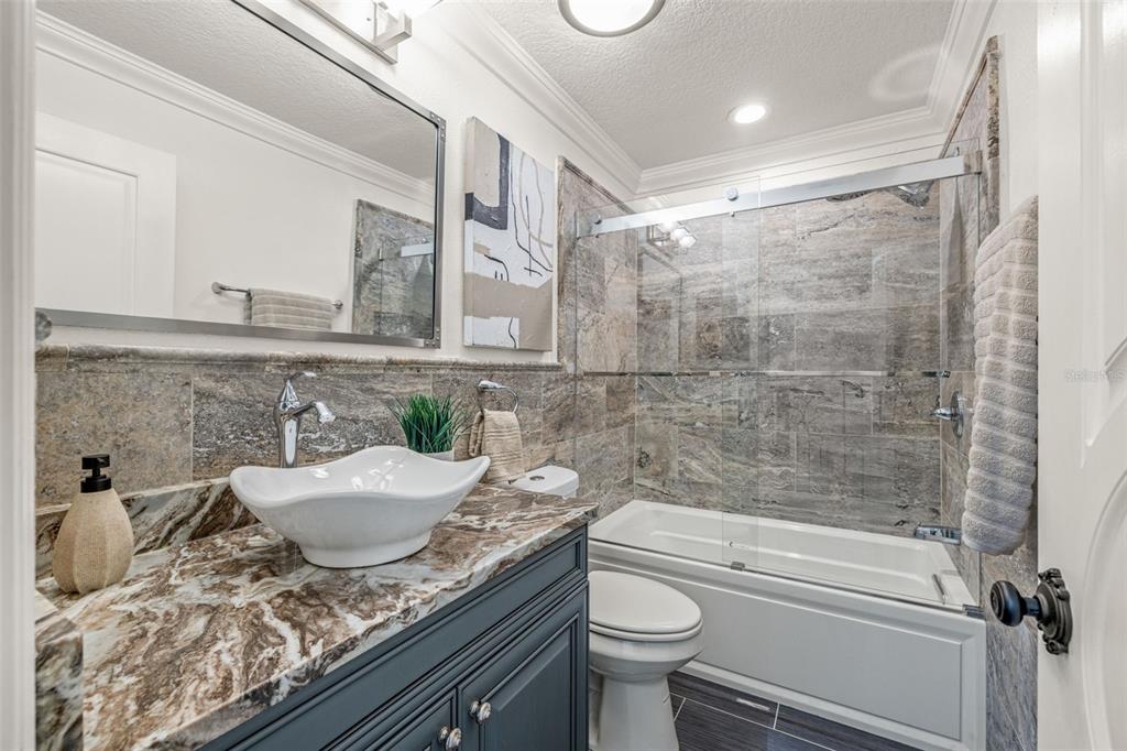 533 Sandy Hook Road Treasure Island, FL 33706 - Photo 26 of 46 a bathroom with a granite countertop sink a toilet and bathtub