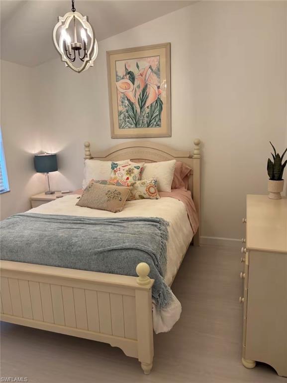 14993 Rivers Edge Court, Unit 246 Fort Myers, FL 33908 - Photo 8 of 23 a bedroom with a bed and a chandelier