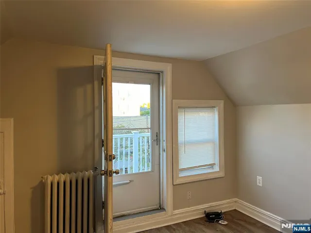 an empty room with wooden floor and mirror