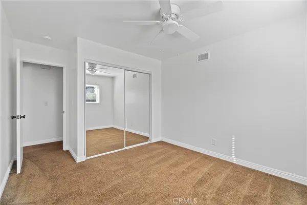an empty room with closet and a chandelier fan