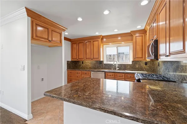 a kitchen with stainless steel appliances granite countertop a refrigerator a stove and a sink with granite countertops