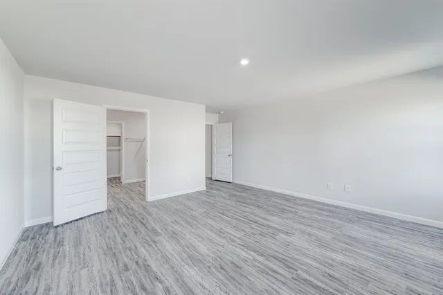 a view of an empty room with wooden floor and closet