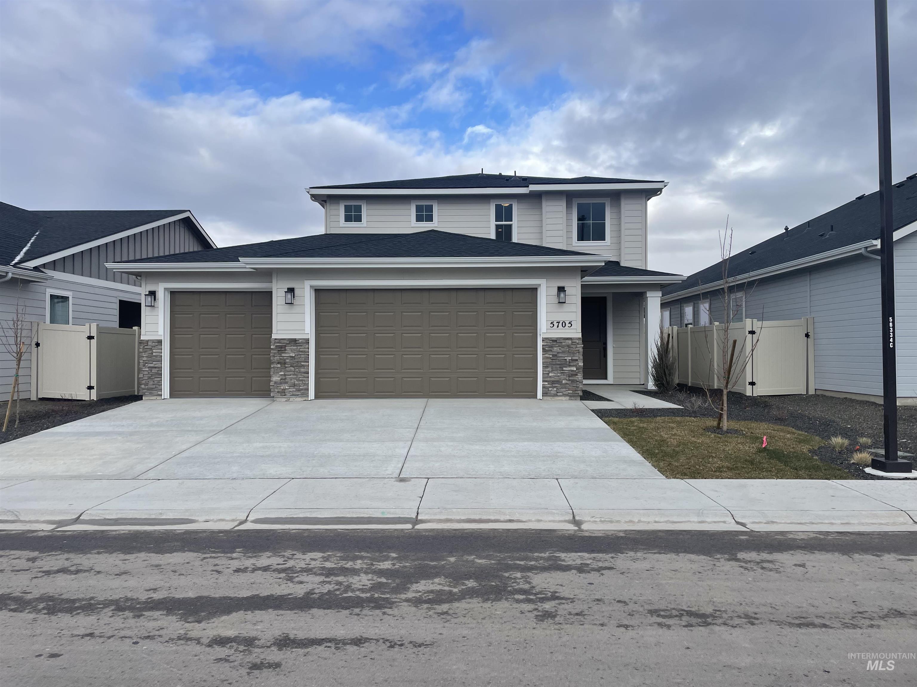 View of front of home with a gate, stone siding, and a garage