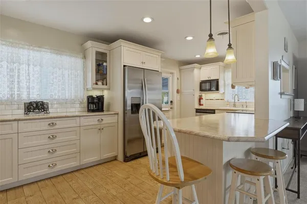 a kitchen with stainless steel appliances kitchen island granite countertop a refrigerator a stove a sink dishwasher and a dining table with chairs