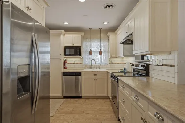 a kitchen with a refrigerator sink and white cabinets