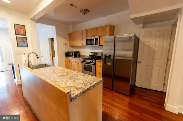 a kitchen with stainless steel appliances granite countertop a refrigerator a stove and a wooden floors