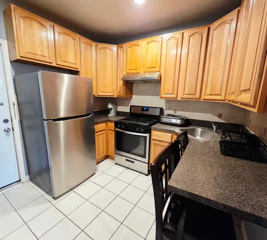 a kitchen with a refrigerator a stove top oven a sink and cabinets