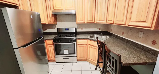 a kitchen with stainless steel appliances granite countertop a refrigerator a sink and white cabinets