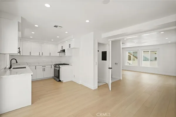 a kitchen with stainless steel appliances granite countertop a sink cabinets and wooden floor