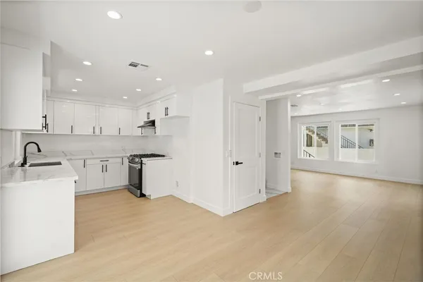 a large kitchen with a large counter top a sink stainless steel appliances and cabinets