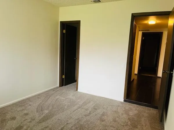 a view of an empty room with closet and a window