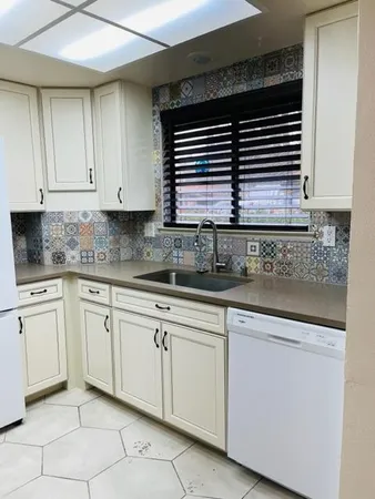 a kitchen with granite countertop white cabinets white appliances and a sink
