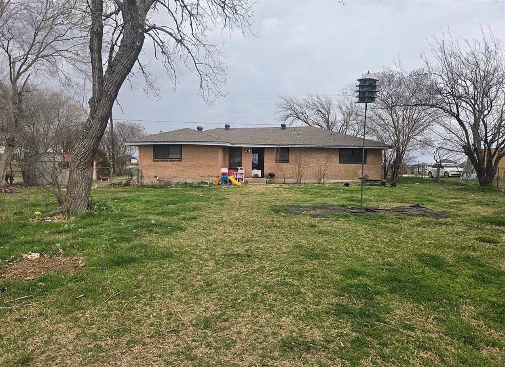 4378 Old Fort Worth Road Midlothian, TX 76065 - Photo 5 of 6 The property features a brick exterior, a dark shingle roof, and a grassy yard with mature trees