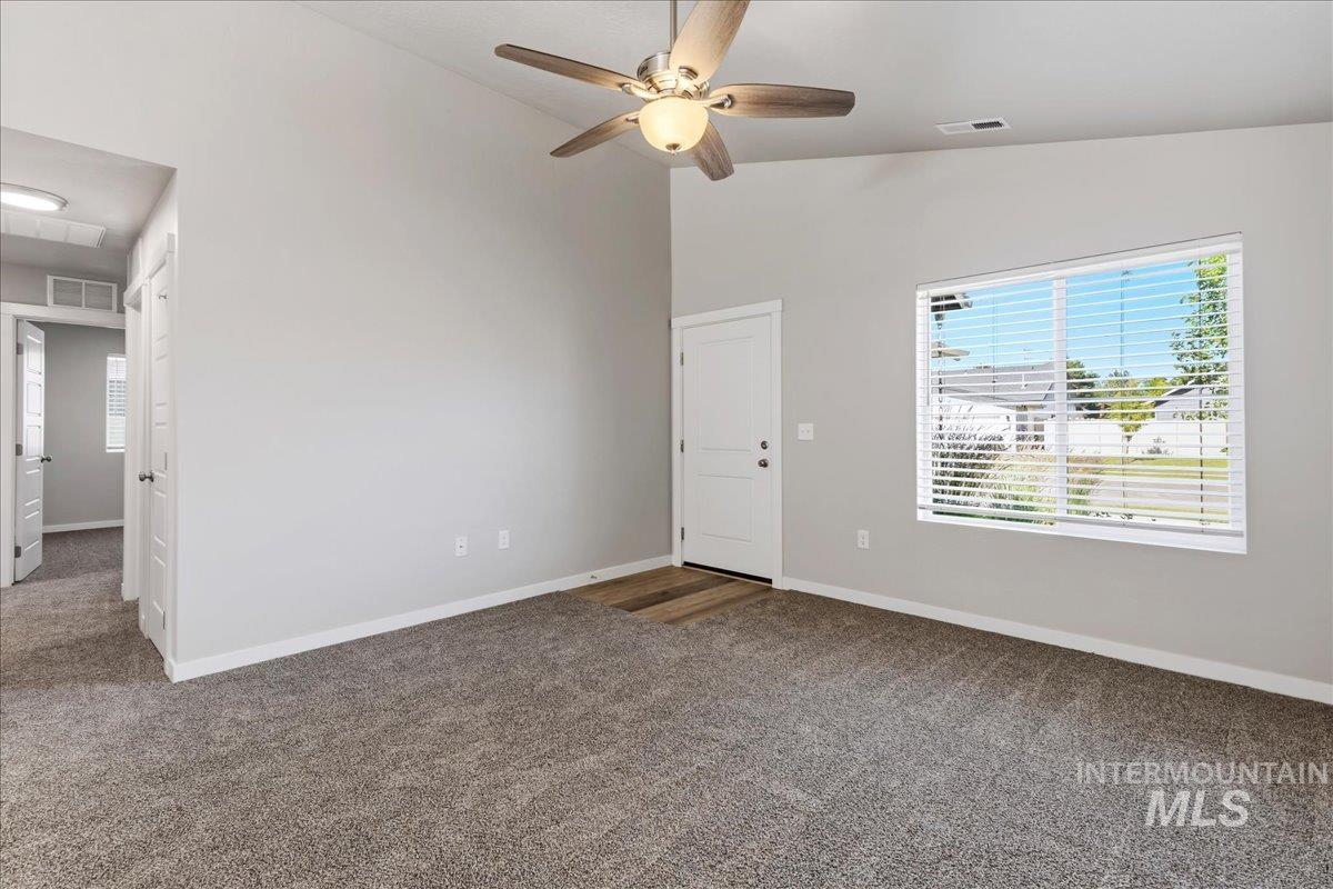 3091 S Green Boise, ID 83709 - Photo 6 of 27 Spacious room featuring vaulted ceilings, a ceiling fan with integrated lighting, a large window with horizontal blinds, and neutral-toned carpeting