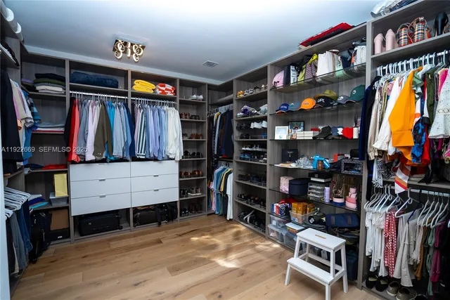 a view of walk in closet with clothes and shoes