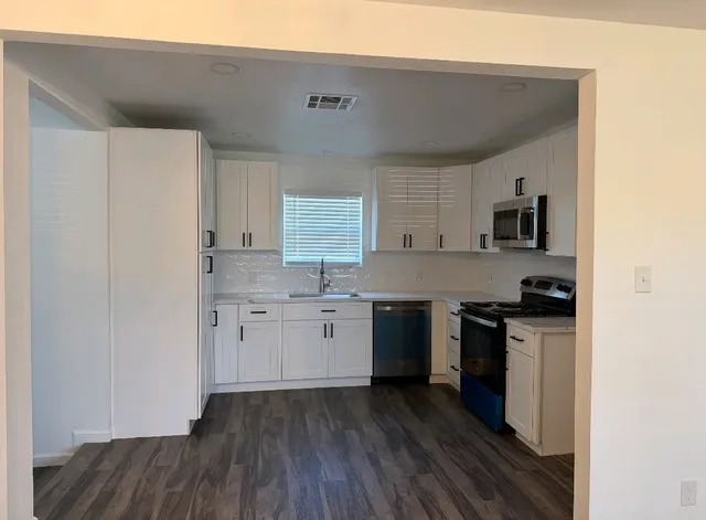 a kitchen with granite countertop a stove top oven sink and cabinets