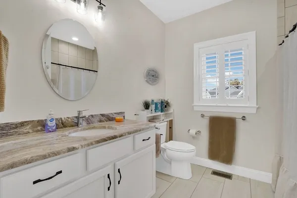 a bathroom with a granite countertop toilet a sink and a mirror