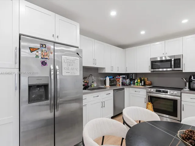 a kitchen with stainless steel appliances a refrigerator stove and white cabinets