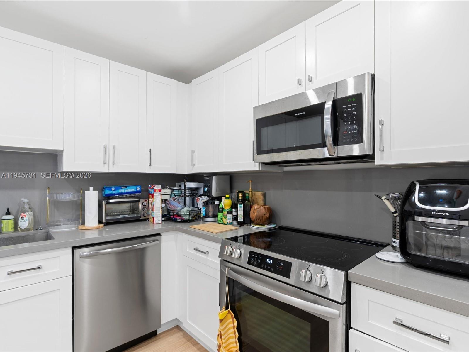 6510 Southwest 59th Place South Miami, FL 33143 - Photo 12 of 23 a kitchen with stainless steel appliances granite countertop white cabinets a stove a microwave and a hard wood floors