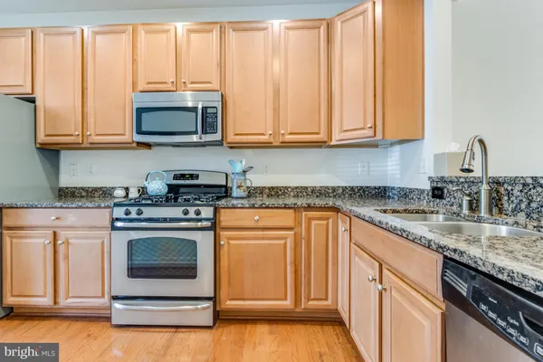 a kitchen with stainless steel appliances granite countertop a stove a sink and a microwave