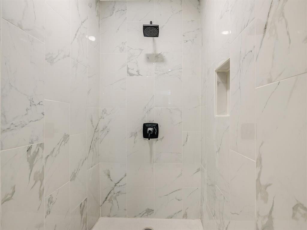 7004 Craybrough Circle Austin, TX 78724 - Photo 10 of 19 Marble-look tile cladding the shower walls offers a sleek, pristine bathing environment.