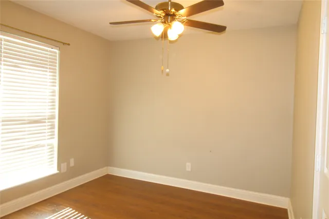 an empty room with a window and a fan
