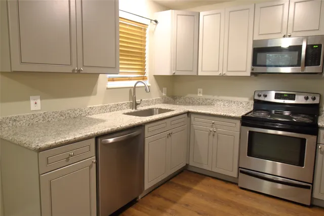 a kitchen with granite countertop cabinets stainless steel appliances and a sink