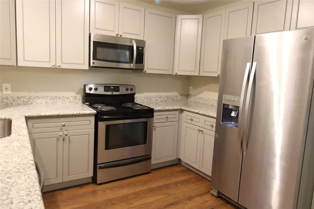 a kitchen with stainless steel appliances white cabinets white stove a refrigerator and a microwave