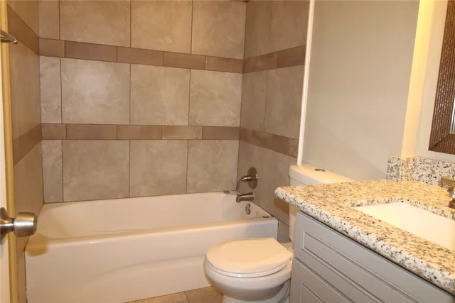 a bathroom with a granite countertop bathtub toilet and sink
