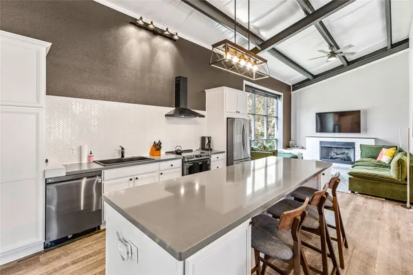 a large white kitchen with a stove a sink dishwasher and a microwave oven with wooden floor
