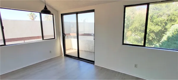 a view of an empty room with wooden floor and windows