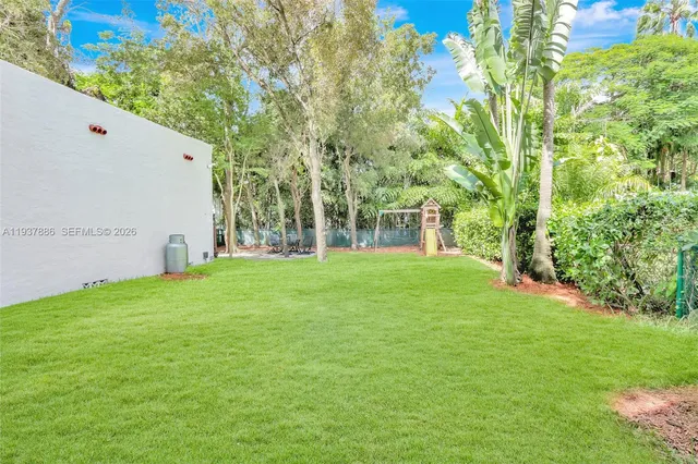 a view of a white house with a big yard and large trees