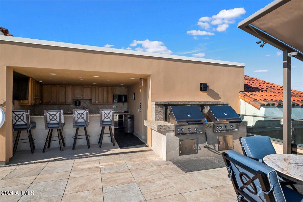 7175 East Camelback Road, Unit 107 Scottsdale, AZ 85251 - Photo 20 of 33 a open kitchen with stainless steel appliances kitchen island granite countertop a table chairs and a refrigerator