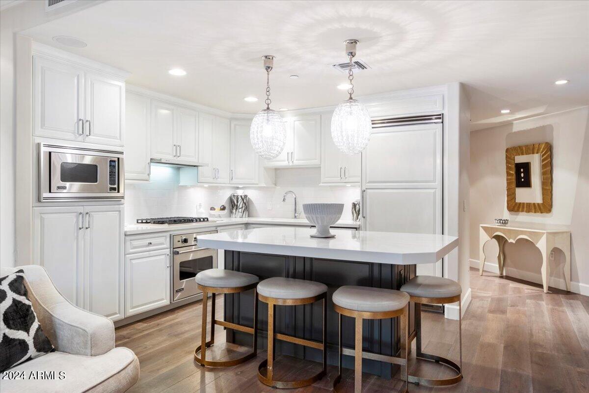 7175 East Camelback Road, Unit 107 Scottsdale, AZ 85251 - Photo 5 of 33 a kitchen with kitchen island granite countertop a dining table chairs stainless steel appliances and cabinets