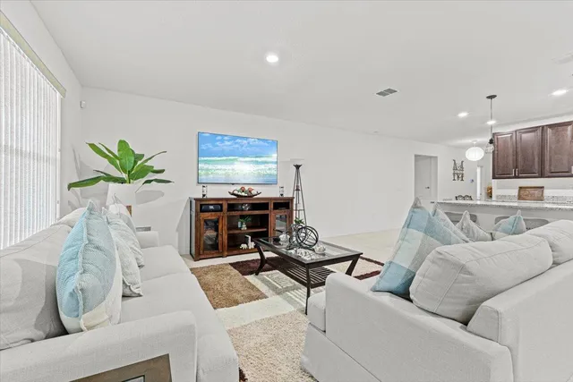 a living room with furniture and a flat screen tv with kitchen view