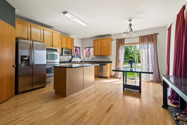 a kitchen with stainless steel appliances granite countertop a stove top oven a sink dishwasher a dining table and chairs with wooden floor