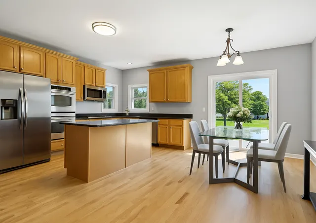 a living room with stainless steel appliances kitchen island granite countertop a couch a dining table and chairs