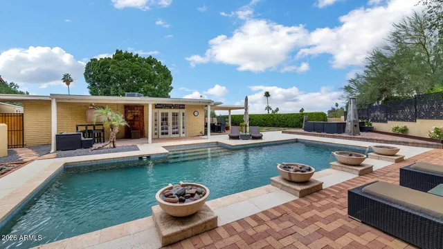 a view of a swimming pool and lounge chairs in back yard of a house