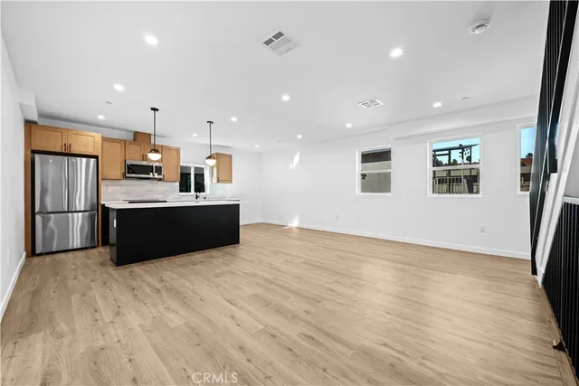 a view of kitchen with stainless steel appliances kitchen island wooden floor and window